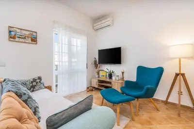 a living room with a couch and a chair and a tv at Sunny Flat w/ Balcony near the Sea by HostWise in Albufeira