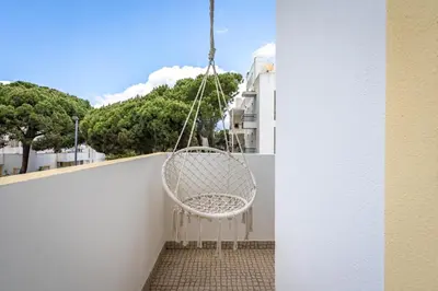 a white chair hanging from a balcony at Sunny Flat w/ Balcony near the Sea by HostWise in Albufeira