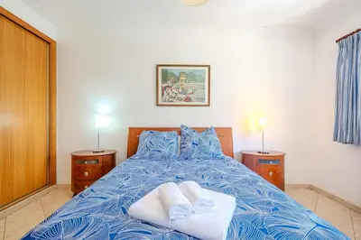 a bedroom with a blue bed with towels on it at Apartmento Estrela de Albufeira Old Town Beach in Albufeira