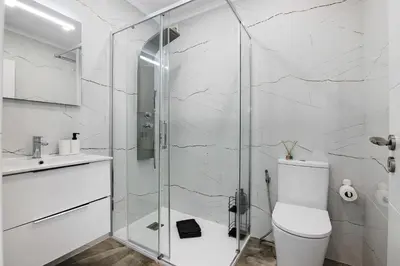 a bathroom with a toilet and a glass shower at Amazing Oura Beach Apartment in Albufeira