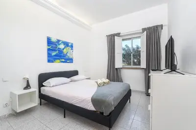 a bedroom with a bed and a flat screen tv at Blife Riamya private rooms in Faro