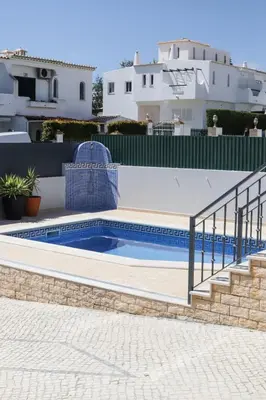 a swimming pool with a staircase next to a house at Silver Globe in Albufeira