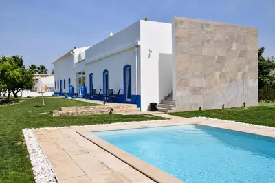 a villa with a swimming pool in front of a building at Quinta da Pi Silveira in Loulé