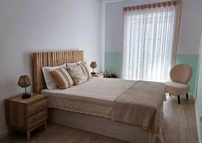 a bedroom with a bed with a chair and a window at Grey and Green, modern 2-bedroom apartment, AC, top location at faro's historic centre in Faro