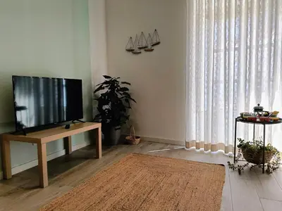 a living room with a flat screen tv and a table at Grey and Green, modern 2-bedroom apartment, AC, top location at faro's historic centre in Faro