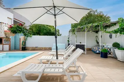 a group of chairs and an umbrella next to a pool at Maison Du Soleil by Seareen in Albufeira