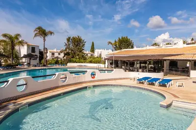 a swimming pool at a resort with tables and chairs at Apartamento Sol & Mar by Portucasa in Albufeira