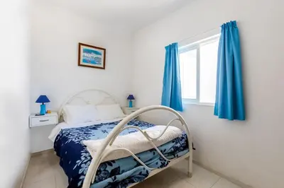 a bedroom with a bed with blue curtains and a window at Maison A Quinta V1 4 Personnes in Ferreiras
