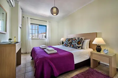 a bedroom with a large bed with a purple blanket at Rebela 1st Algarve Villa Holidays in Albufeira