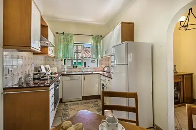a kitchen with a table and a white refrigerator at Rebela GF by Algarve Villa Holidays in Albufeira