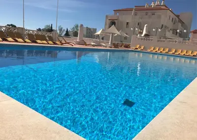 a large swimming pool with chairs and blue water at Amazing Sea View Studio w Pool in Albufeira