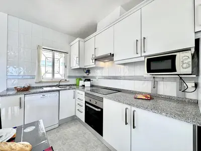 a white kitchen with white cabinets and a microwave at Albufeira Tropical View 2 by Homing in Sesmarias