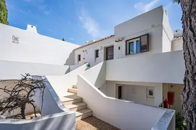 a white house with stairs and a tree at Sunny Flat with a Balcony & Pool by HostWise in Albufeira