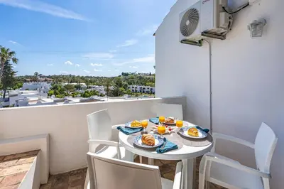 a table with plates of food on a balcony at Sunny Flat with a Balcony & Pool by HostWise in Albufeira