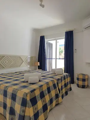 a bedroom with a bed with blue curtains and a window at Balaia Golf Village 122 in Albufeira