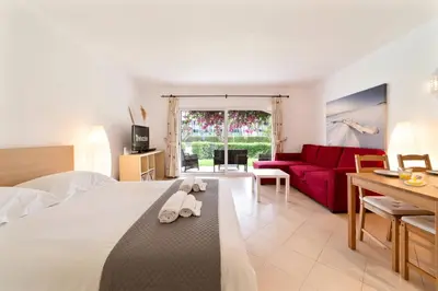 a hotel room with a bed and a red couch at Apt 77 - São Rafael by HelloVacations in Albufeira