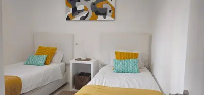 a bedroom with two beds and a painting on the wall at Casa dos Sinos Beach Apartment 1 with Roof Terrace in Albufeira