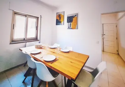 a dining room table with white chairs and a wooden table at Casa dos Sinos Beach Apartment 1 with Roof Terrace in Albufeira