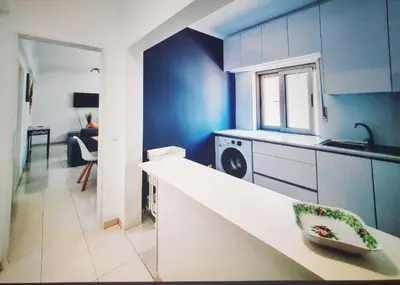 a kitchen with a white counter and a blue wall at Casa dos Sinos Beach Apartment 1 with Roof Terrace in Albufeira