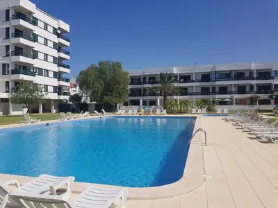 a large swimming pool with lounge chairs and a building at Stork nest in Vilamoura
