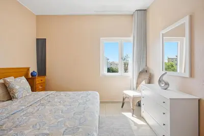 a bedroom with a bed and a dresser and two windows at Stork nest in Vilamoura