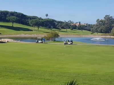 two golf carts parked on a green next to a lake at Stork nest in Vilamoura