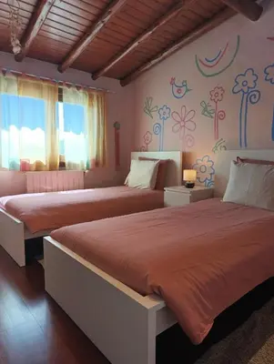 two beds in a bedroom with flowers on the wall at Villa Inês in Guia