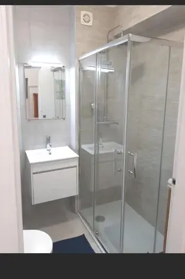 a bathroom with a glass shower and a sink at T0 close to the beach and the city center in Albufeira