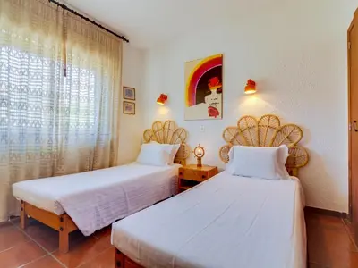 two beds in a room with a window at Apartamento Forte Novo no centro de Quarteira in Quarteira