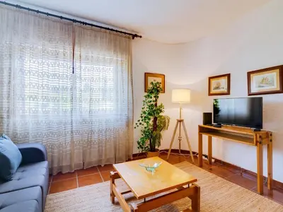 a living room with a blue couch and a tv at Apartamento Forte Novo no centro de Quarteira in Quarteira