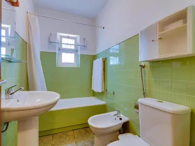 a green bathroom with a toilet and a sink at Apartamento Forte Novo no centro de Quarteira in Quarteira