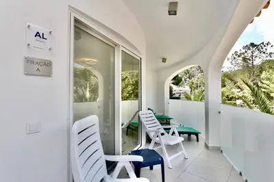 a balcony with white chairs and a green table at Monte Verde A,Lar Linda - CD 293 Cleverdetails, Sleeps 2 adults and 2 children, 4 salted water pools in Quarteira