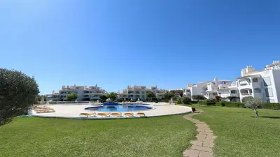 a view of a swimming pool with chairs and buildings at Monte Verde A,Lar Linda - CD 293 Cleverdetails, Sleeps 2 adults and 2 children, 4 salted water pools in Quarteira