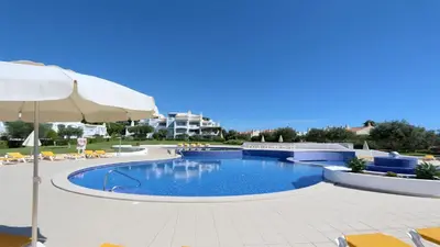 a large swimming pool with an umbrella and chairs at Monte Verde A,Lar Linda - CD 293 Cleverdetails, Sleeps 2 adults and 2 children, 4 salted water pools in Quarteira
