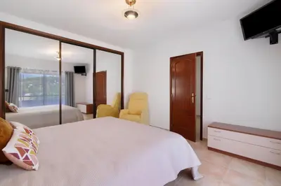 a bedroom with a large white bed and a television at Villa Neves in Albufeira