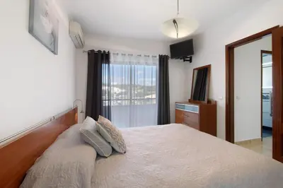 a bedroom with a white bed and a large window at Villa Neves in Albufeira