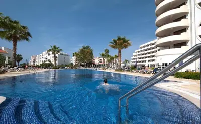 a person swimming in a swimming pool next to a building at Hotel Vila Galé Cerro Alagoa in Albufeira