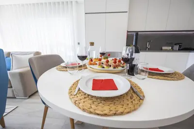 a white table with a plate of food and wine glasses at Terracos de Quarteira Orange by Real Properties in Quarteira