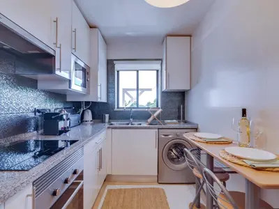 a kitchen with white cabinets and a washer at AL Vilamoura Porto Marina in Vilamoura