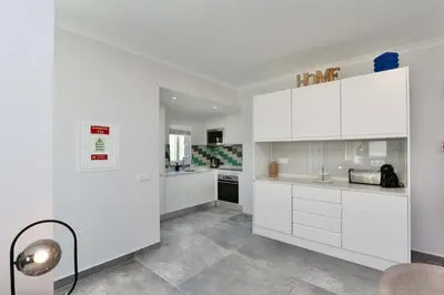 a white kitchen with white cabinets and a lamp at Monte Verde B CD 294 - Cleverdetails, Sleeps 2 adults and 2 children, 4 salted water pools in Quarteira