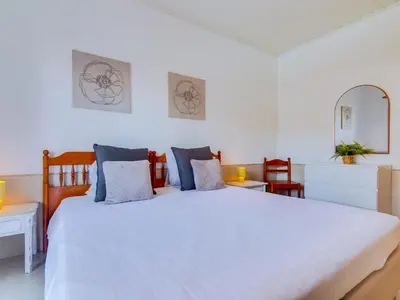 a bedroom with a large white bed with blue pillows at Apartamento Alvaflor com Piscina – Vilamoura in Quarteira