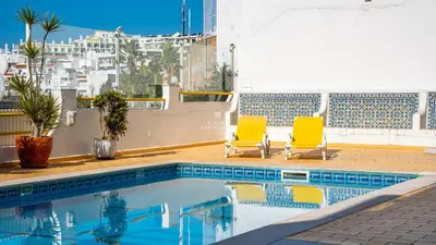 two yellow chairs sitting next to a swimming pool at Downtown Studio - By D`alma Portuguesa in Albufeira