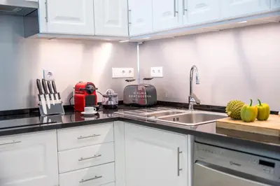 a kitchen with white cabinets and a red appliance at Downtown Studio - By D`alma Portuguesa in Albufeira