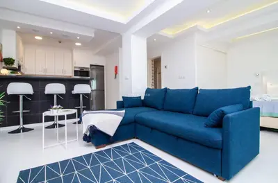 a living room with a blue couch and a kitchen at Downtown Studio - By D`alma Portuguesa in Albufeira