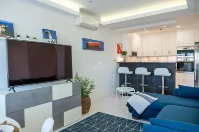a living room with a blue couch and a flat screen tv at Downtown Studio - By D`alma Portuguesa in Albufeira