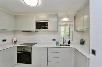 a white kitchen with white cabinets and a sink at Monte Verde C - CD 295, Cleverdetails, Sleeps 2 adults and 2 children, 4 salted water pools in Vilamoura