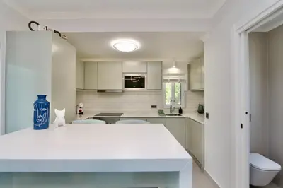 a white kitchen with a blue vase on a table at Monte Verde C - CD 295, Cleverdetails, Sleeps 2 adults and 2 children, 4 salted water pools in Vilamoura