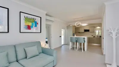 a living room with a blue couch and a kitchen at Monte Verde C - CD 295, Cleverdetails, Sleeps 2 adults and 2 children, 4 salted water pools in Vilamoura