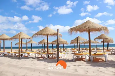 a beach with chairs and umbrellas on the sand at #312 Ocean Outlook by Home Holidays in Páteo