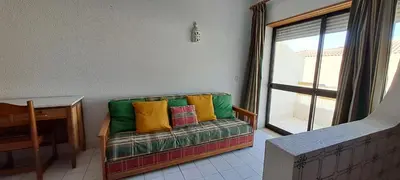 a couch with colorful pillows in a room with a window at Caranguejo Apartment in Albufeira